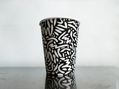 Black and White Illustrated Coffee Cup on Metal Table - A black and white cup with an illustrated white pattern on it