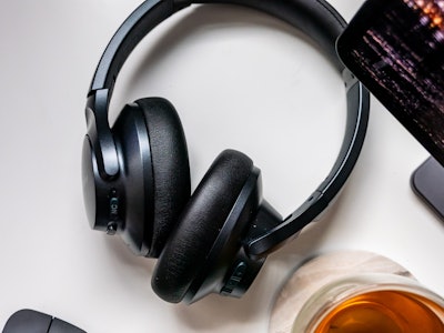Headphones, Tablet, and Tea on Desk - A pair of black headphones next to a glass of coffee