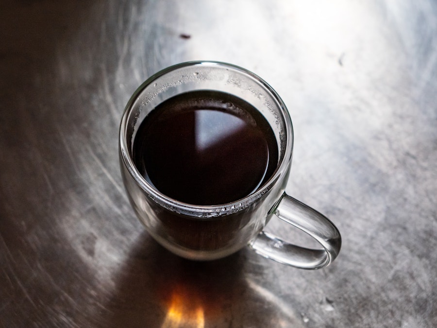 Photo: A glass cup of coffee on a metal counter