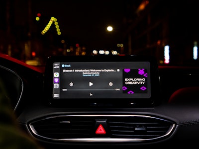 Podcast Playing in Car - A screen on the dashboard of a car at night