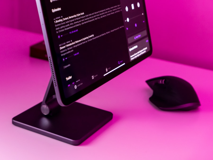 Photo: A tablet and mouse on a desk with pink lighting