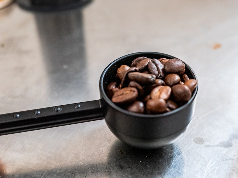 Photo: A scoop of coffee beans on a metal countertop 