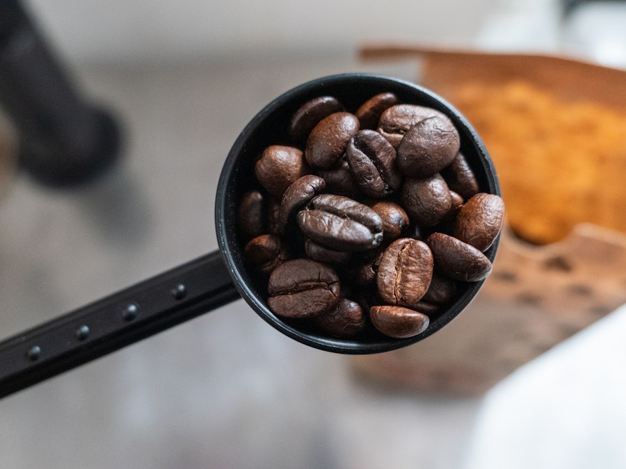 Photo: A black scooper filled with coffee beans in focus