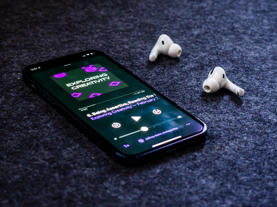 Photo: A smartphone and earbuds on a desk mat