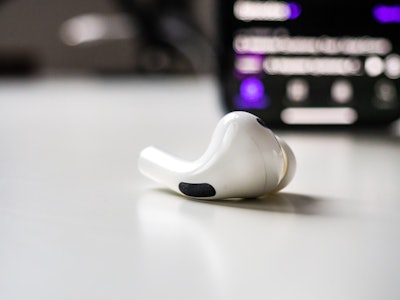 Earbud on White Desk with Phone - A white earbuds and smartphone on a white desk