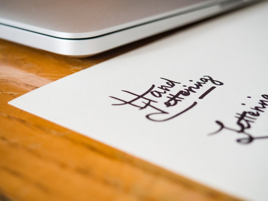 Photo: Lettering and Laptop on Wooden Desk