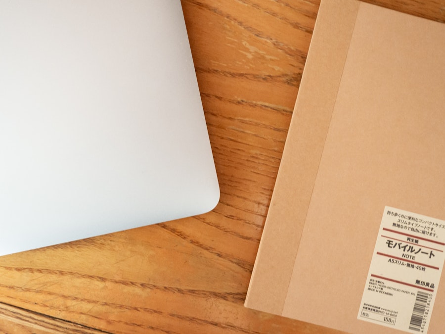 Photo: A laptop and a brown notebook on a wooden desk