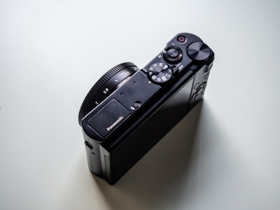 Black Camera on White Desk - A black camera with dials and buttons on a white desk