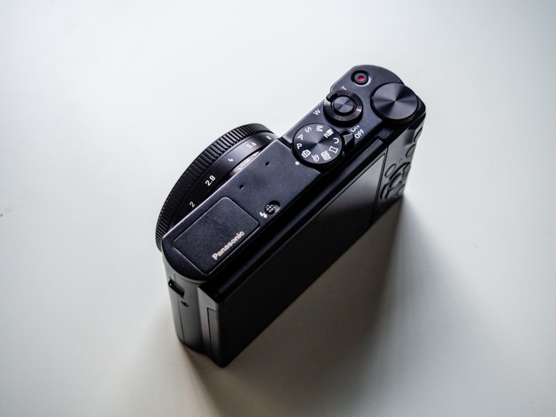 Photo: A black camera with dials and buttons on a white desk