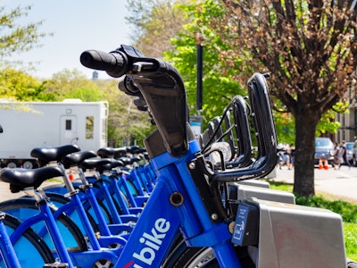 Bicycles - A row of blue bicycles in front of a white trailer outside a park