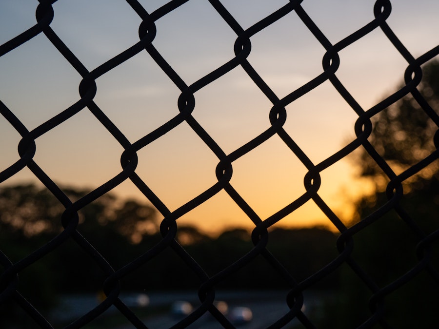 Photo: A close up of a silhouetted fence during sunset 