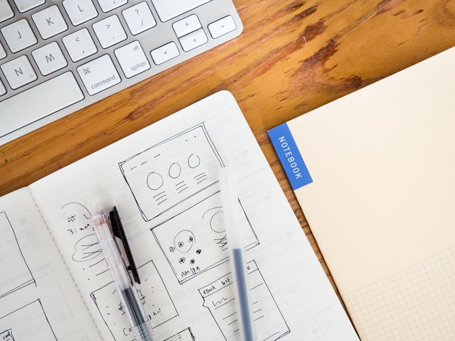 Photo: Wooden Desk with Keyboard and Sketchbooks