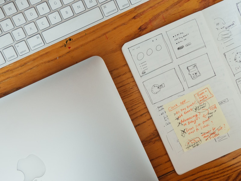 Photo: Wooden Desk with Keyboard, Laptop, and Sketchbook