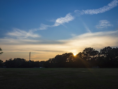 Sunset and Clouds - A sun setting over a field with silhouetted trees