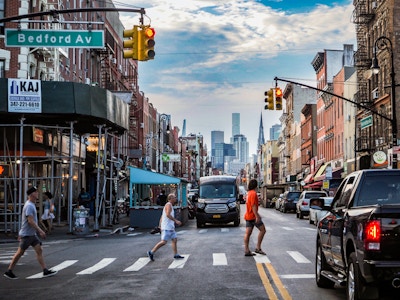 Brooklyn Street with Cars, People, and Buildings - A city street with cars and people crossing the street