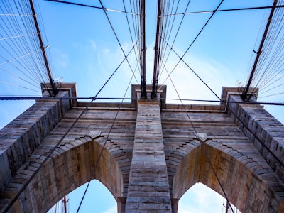 Brooklyn Bridge Under Blue Sky - Looking up at the Brooklyn Bridge with many cables under blue sky and clouds