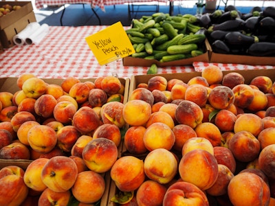 Peaches on Table at Farmers Market - A group of peaches and cucumbers for sale at a farmers market 