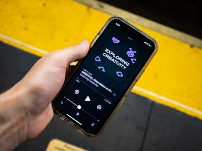 Phone with Podcast on Subway Platform - A hand holding a phone in a subway station listening to a podcast 