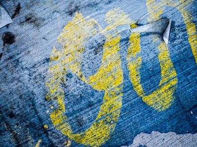 Paint and Sticker on Concrete - Yellow paint graffiti on a black and blue surface