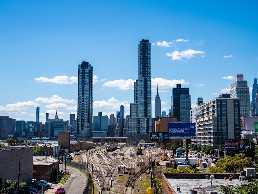 Photo: A city skyline with tall buildings and railroad tracks