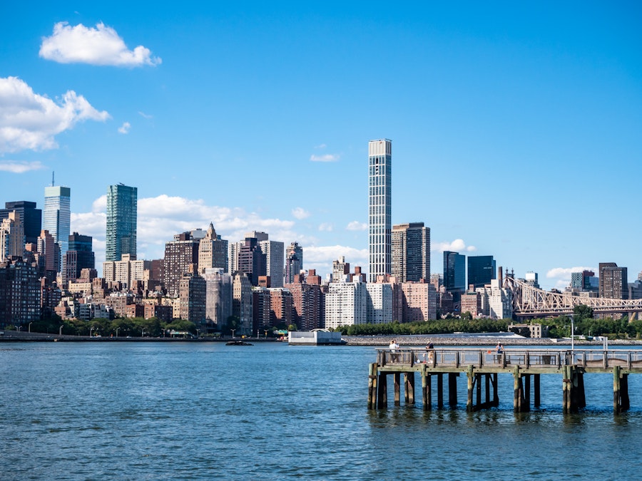 Photo: A city skyline with a dock in the water under blue sky