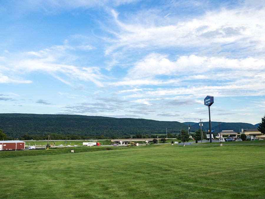 Photo: Grass and Mountains Over Blue Sky