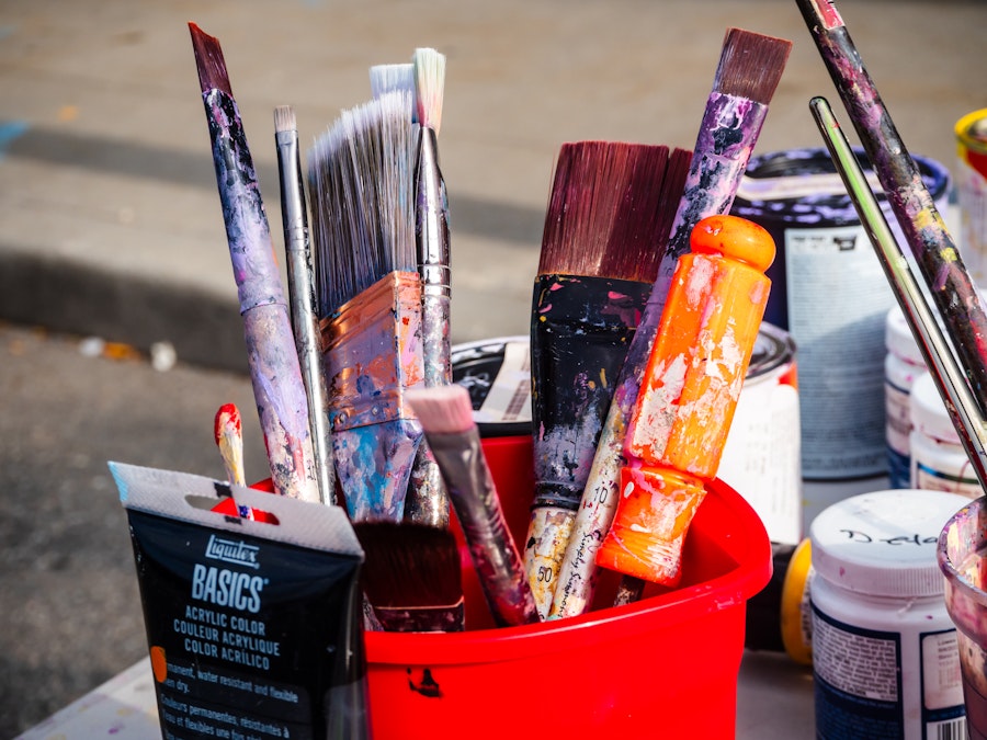 Photo: Many paint brushes with paint splatters in a red bucket