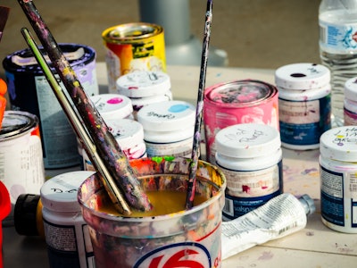 Painting Supplies - Paint cans and paintbrushes in a paint bucket on a table