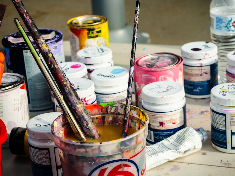 Photo: Paint cans and paintbrushes in a paint bucket on a table