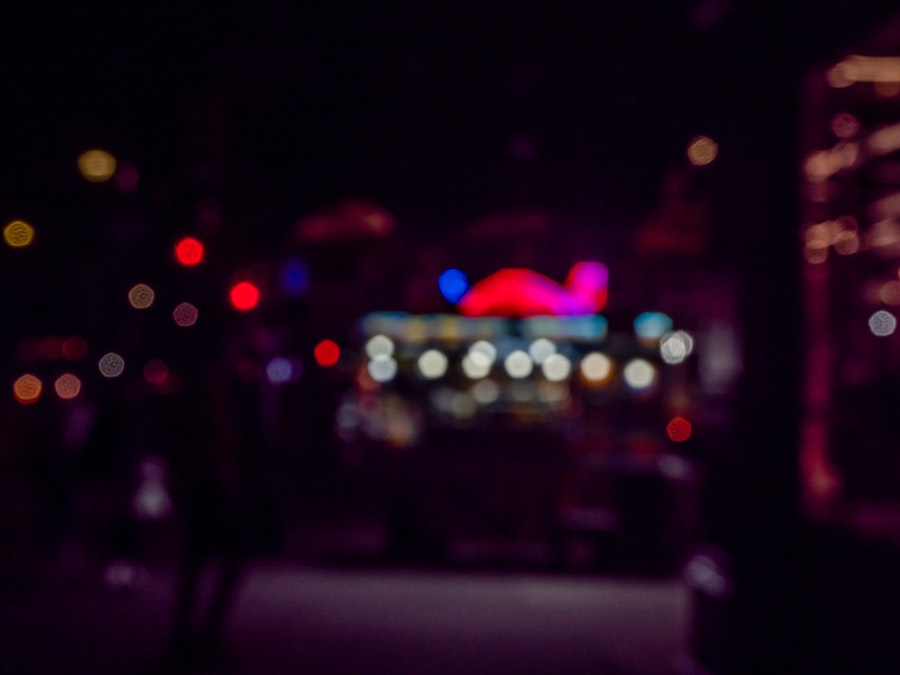 Photo: Blurry image of a building and food stand at night in a city