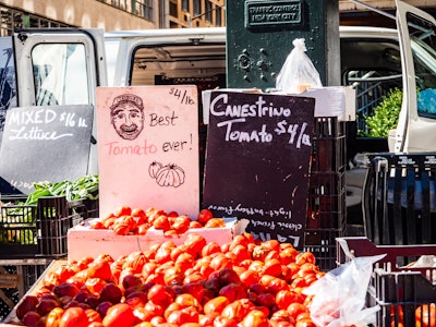 Tomatoes on Sale at Farmers Market - A bunch of tomatoes for sale with a black and white chalkboard sign