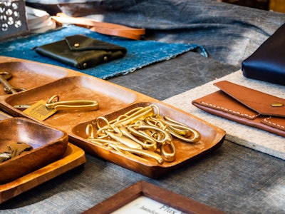 Leather Goods on Table - Trays of gold objects and leather wallets on a table at an artist market