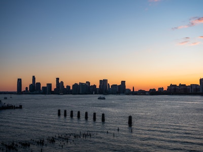 Sunset Over River and Buildings - A city skyline in the water under sunset