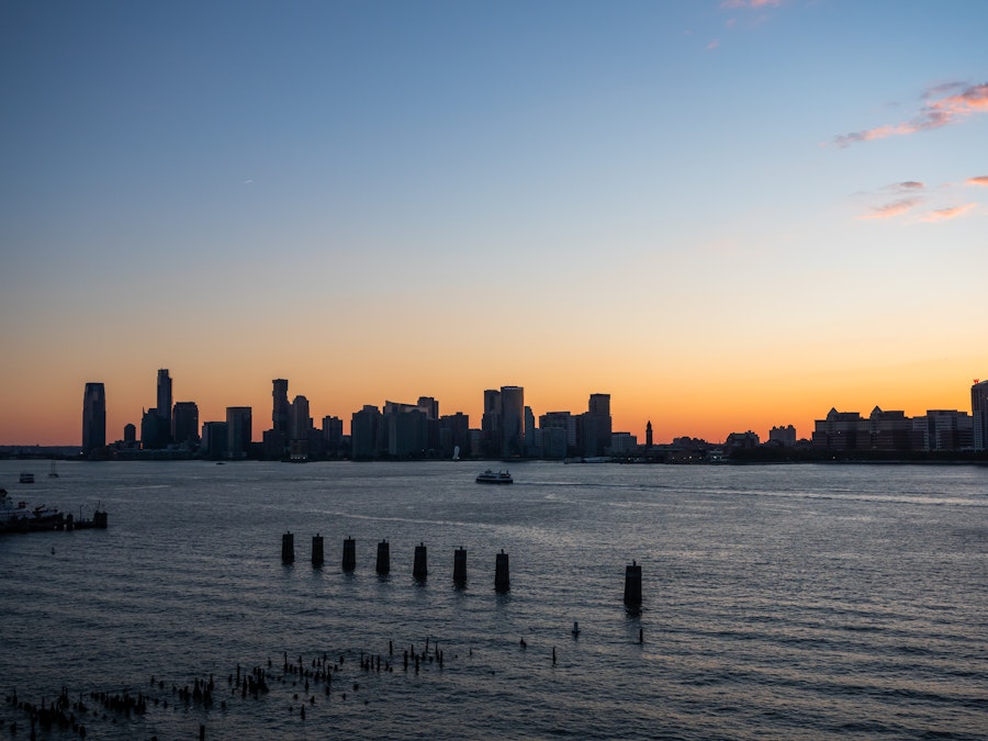 Photo: A city skyline in the water under sunset
