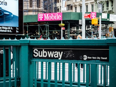 Subway Entrance - Subway entrance stairs with a black sign on a green fence