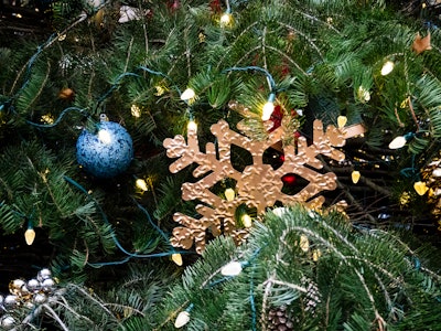 Snowflake Ornament on Christmas Tree - A gold snowflake ornament on a Christmas tree