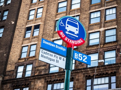 Brooklyn Bus Stop Sign - A bus stop street sign with a building in the background