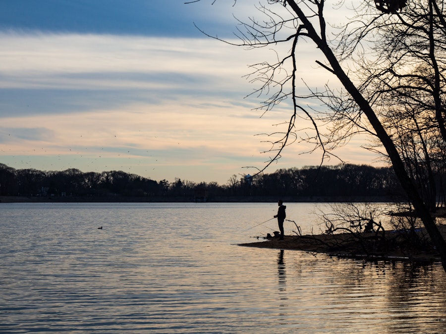 Photo: A person fishing on a lake during sunset 