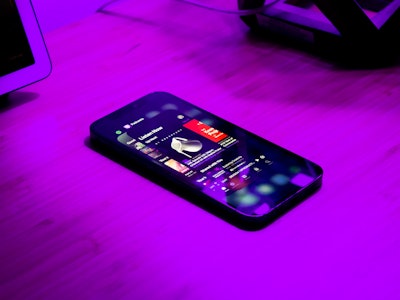 Switching Apps on Phone While Listening to Podcast - A smartphone playing a podcast under purple lighting on a table